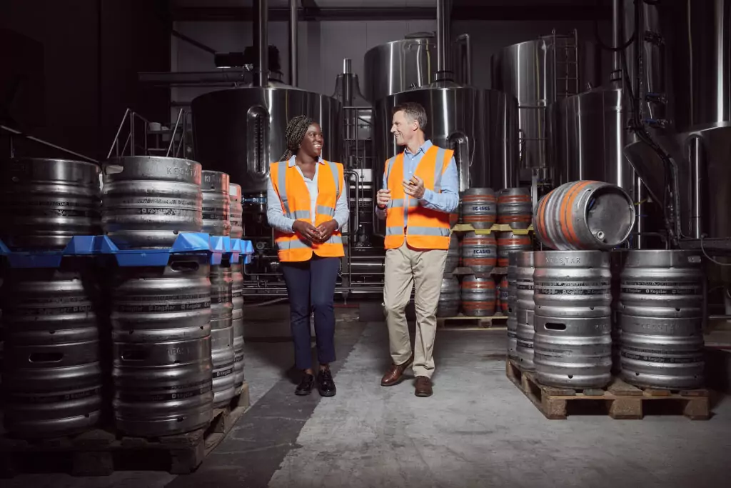 A man and woman speaking in a factory.