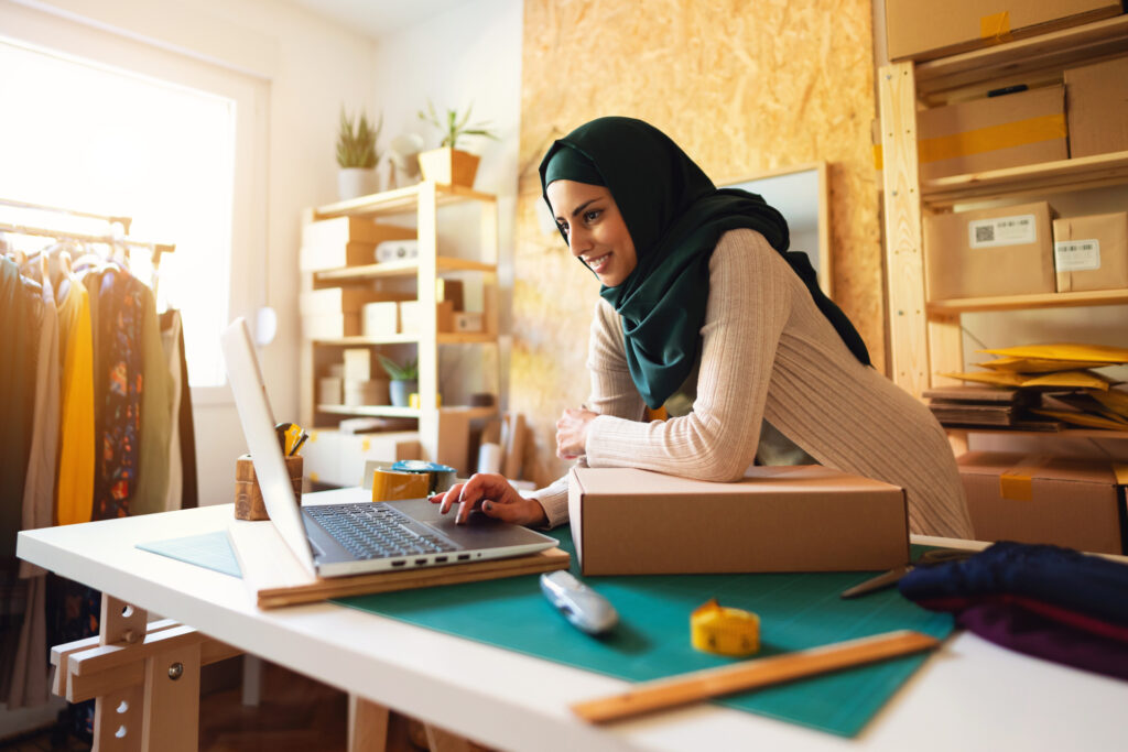 Smiling Muslim businesswoman with hijab using laptop