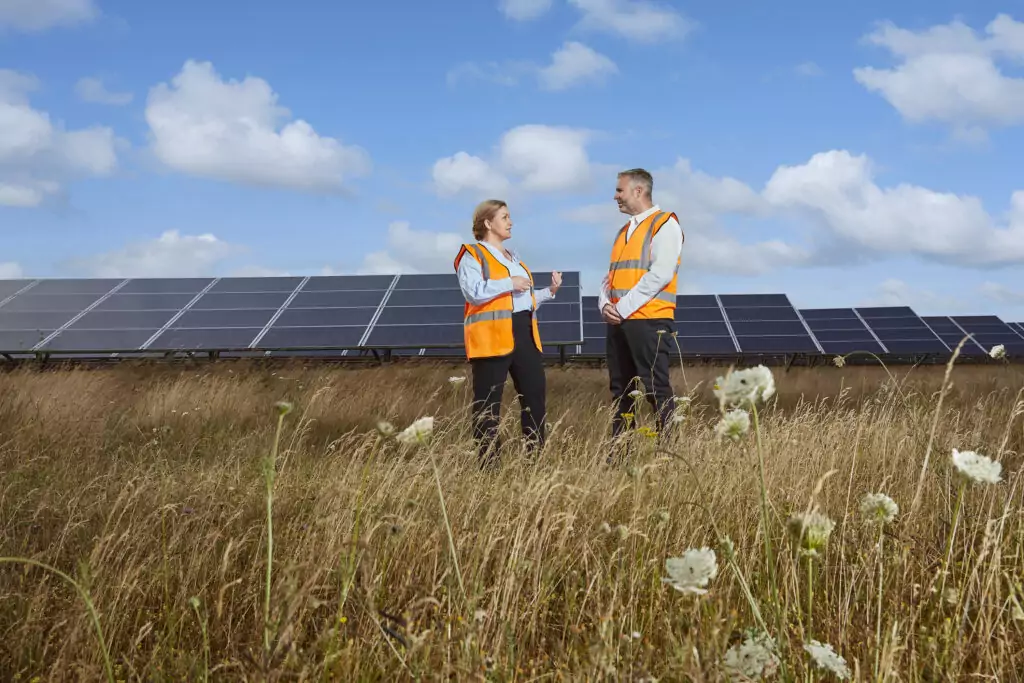 A man and woman talking in front of solar panels.