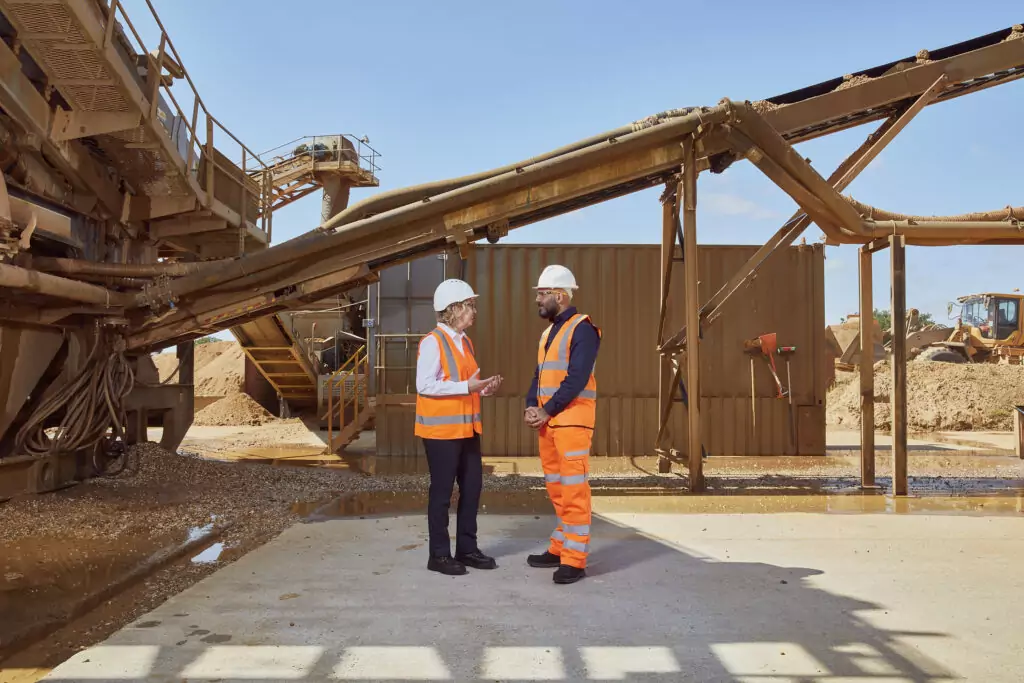 A man and woman speaking on a construction site.