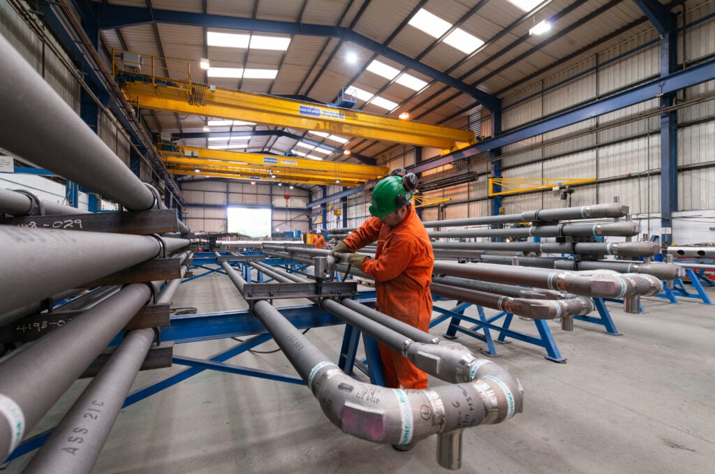 A man working on metal pipes in a factory.