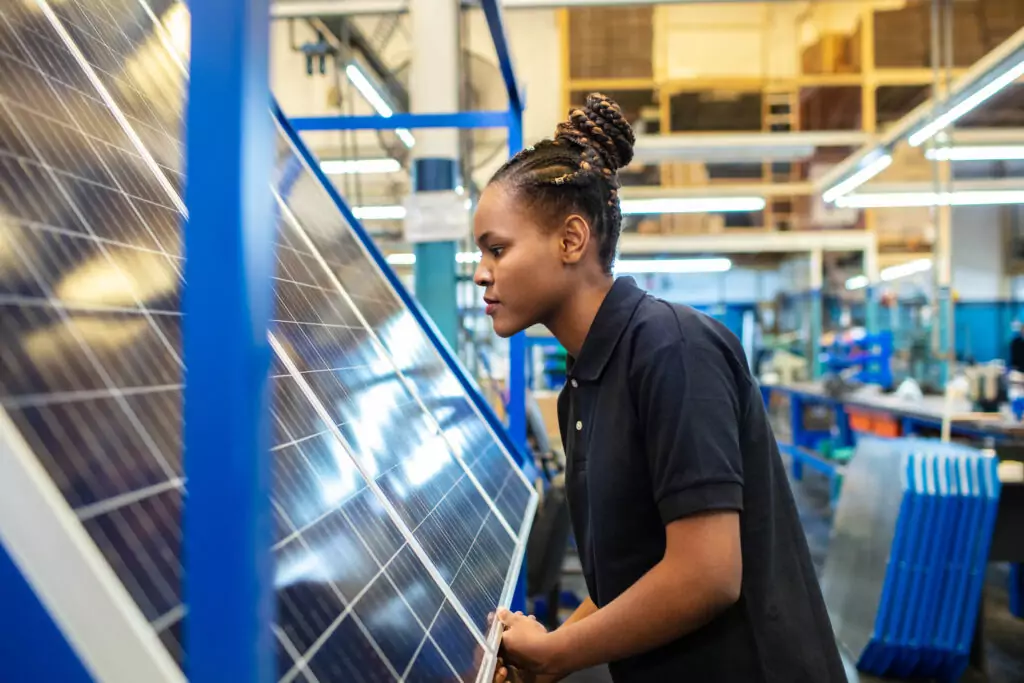 A woman examining a solar panel in a factory.