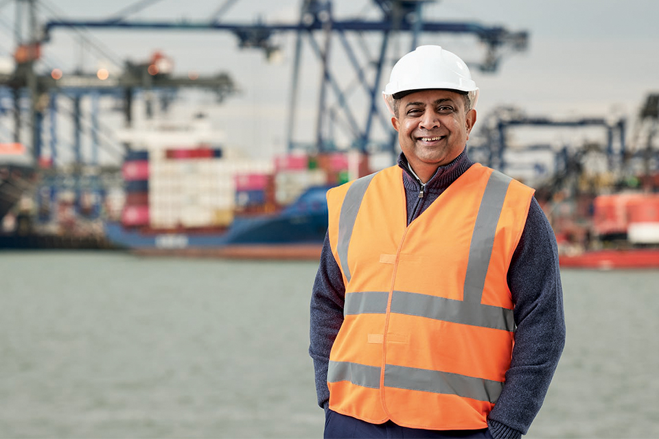 A man in high vis gear stands at a shipping dock