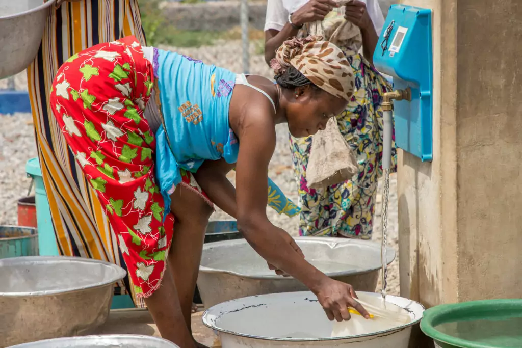 A woman fills a bucket of water at a water pump