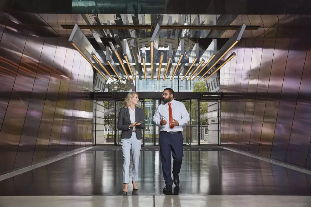 A woman and man walking and talking in an industrial office building