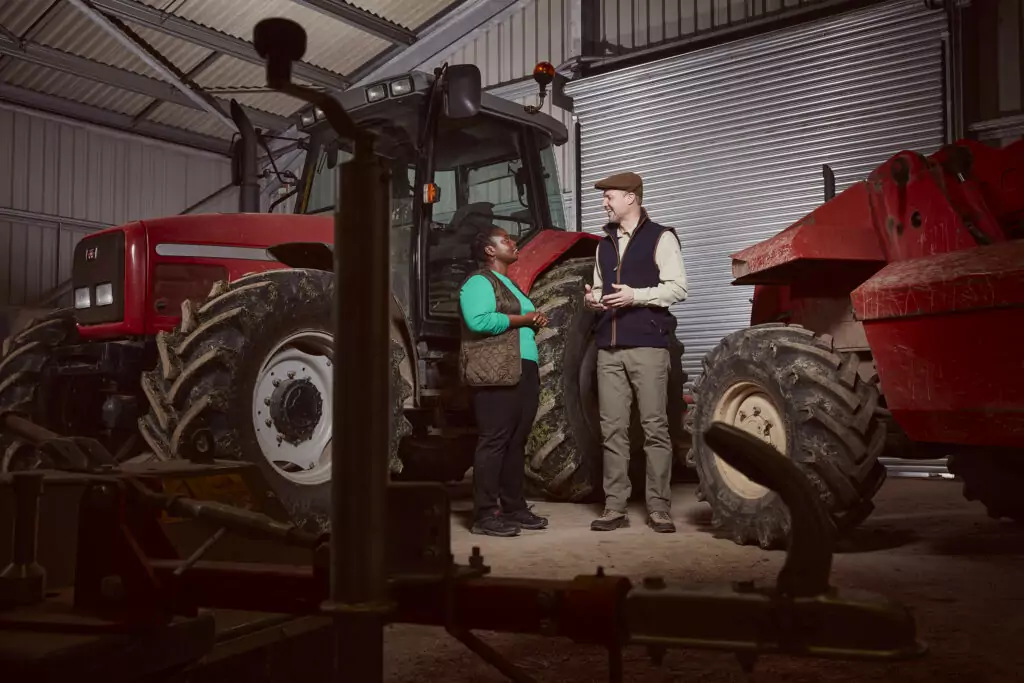 A man and woman speaking in front of a tractor