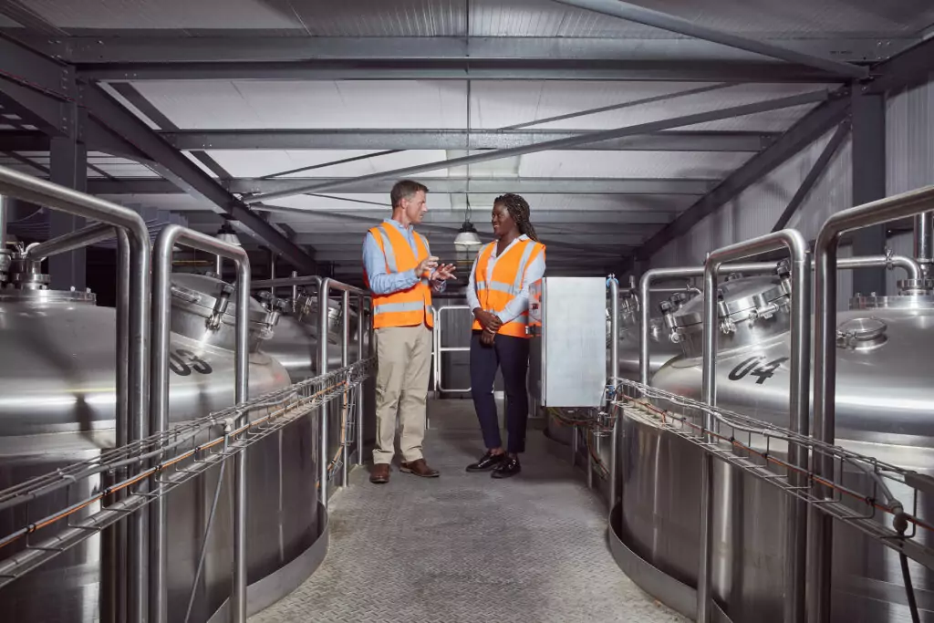 A man and woman speaking in a factory.