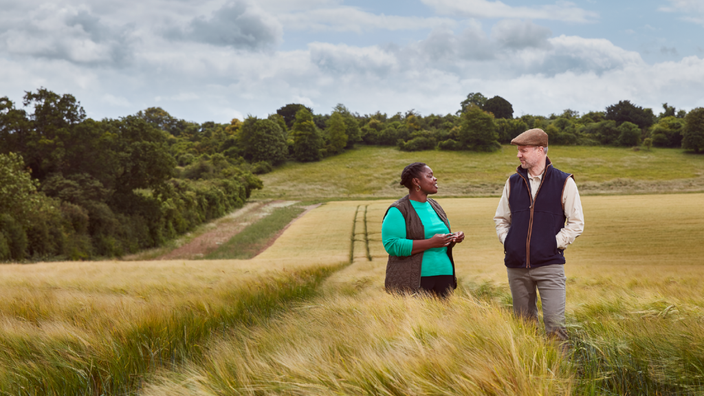 A woman and a man talking in a field.